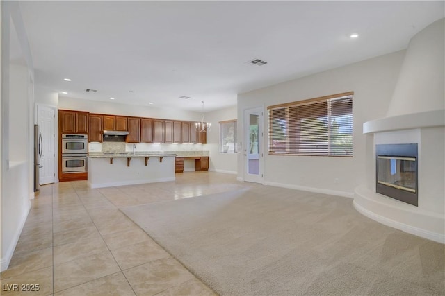 unfurnished living room featuring light tile patterned floors, recessed lighting, a large fireplace, baseboards, and a chandelier