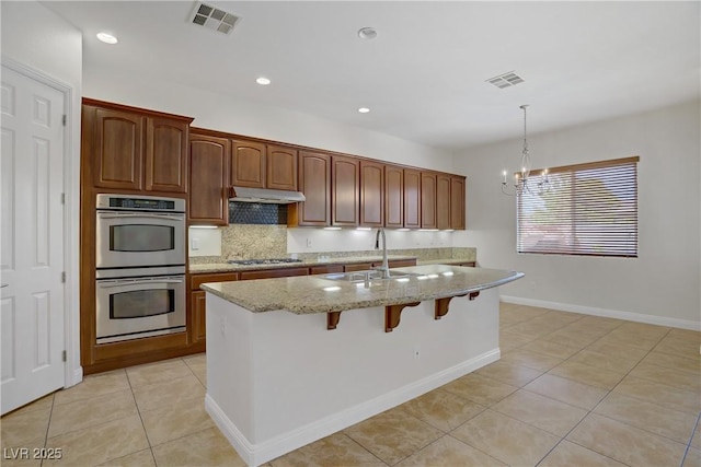 kitchen with stainless steel appliances, a sink, light tile patterned floors, light stone counters, and recessed lighting
