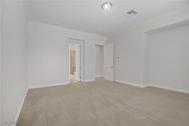 empty room featuring crown molding, light colored carpet, and baseboards