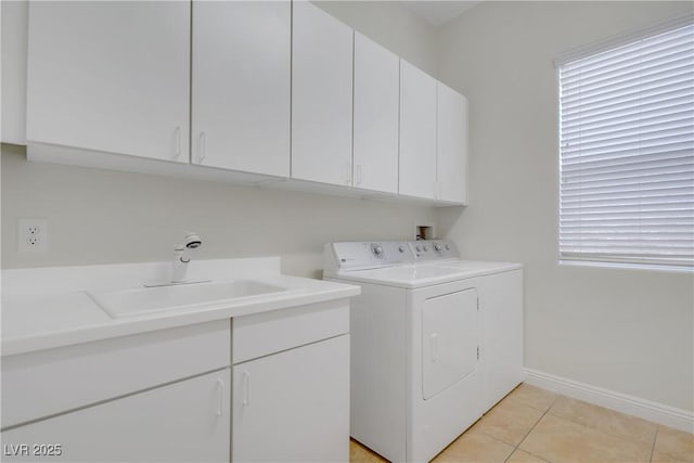 clothes washing area with cabinet space, washer and dryer, baseboards, and light tile patterned floors