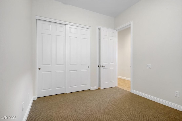 unfurnished bedroom featuring carpet, baseboards, and a closet
