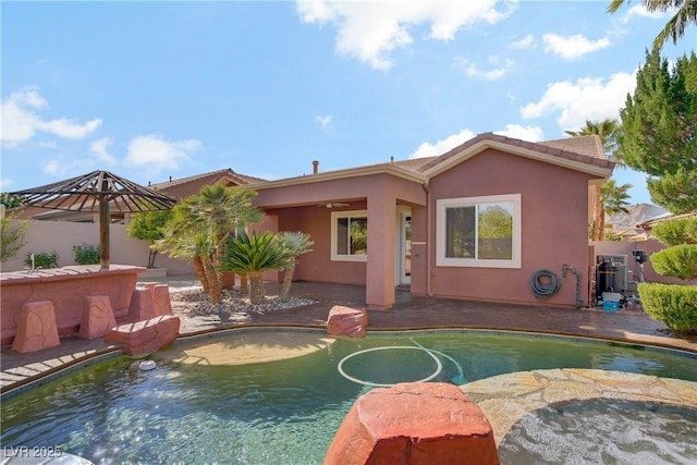 back of house featuring stucco siding, an outdoor pool, a patio area, a ceiling fan, and fence