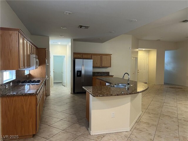 2855 Grande Valley Dr, Las Vegas, NV 89135 - kitchen featuring appliances with stainless steel finishes, a sink, light tile patterned floors, brown cabinetry, and dark stone counters