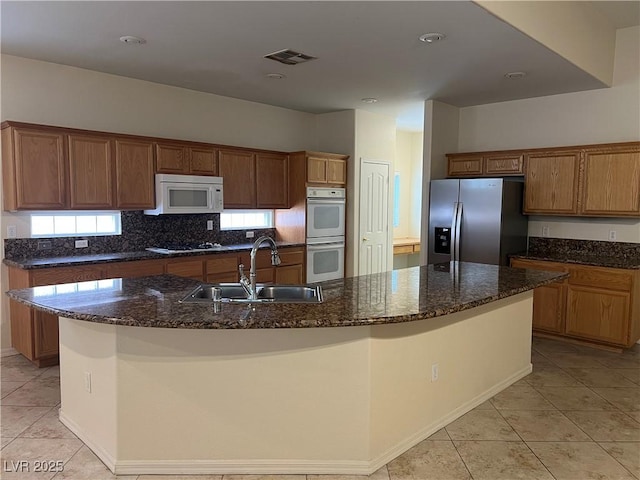 2855 Grande Valley Dr, Las Vegas, NV 89135 - kitchen featuring a sink, white appliances, a large island with sink, light tile patterned flooring, and brown cabinetry