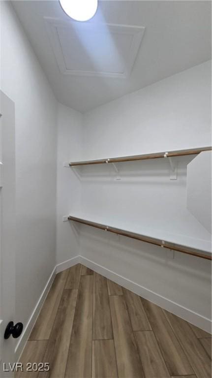 walk in closet with wood finished floors and attic access