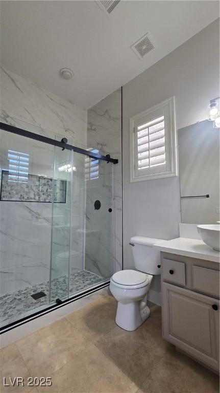 bathroom featuring a marble finish shower, vanity, and toilet