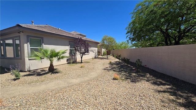 view of side of home with fence and stucco siding