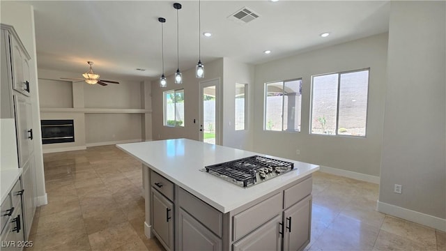 kitchen with stainless steel gas cooktop, open floor plan, a ceiling fan, baseboards, and light countertops