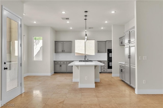 11621 La Mirago Pl, Las Vegas, NV 89138 - kitchen with gray cabinetry, light countertops, a kitchen island, baseboards, and recessed lighting