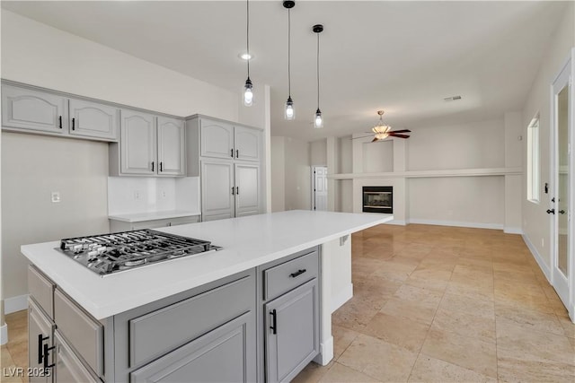 11621 La Mirago Pl, Las Vegas, NV 89138 - kitchen with stainless steel gas stovetop, a ceiling fan, gray cabinets, and a glass covered fireplace