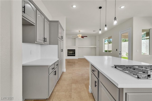 11621 La Mirago Pl, Las Vegas, NV 89138 - kitchen with gray cabinets, stainless steel gas stovetop, ceiling fan, open floor plan, and light countertops