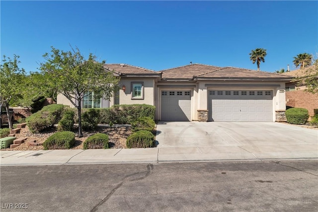 11621 La Mirago Pl, Las Vegas, NV 89138 - view of front of house featuring an attached garage, stucco siding, driveway, a tiled roof, and stone siding