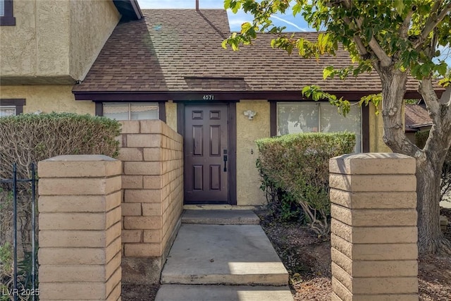 property entrance featuring roof with shingles and stucco siding