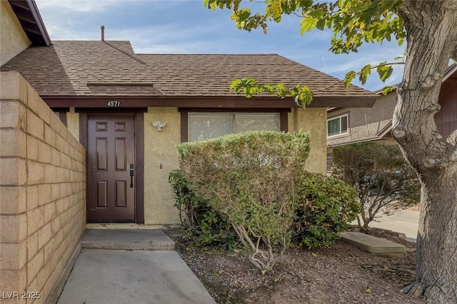 property entrance featuring roof with shingles and stucco siding