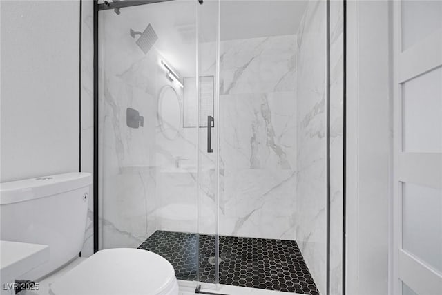 bathroom featuring toilet and a marble finish shower