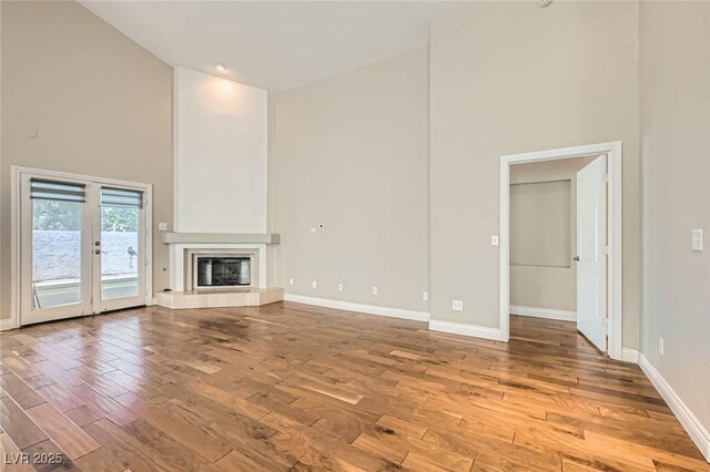 8124 Bay Harbor Dr, Las Vegas, NV 89128 - unfurnished living room with high vaulted ceiling, wood finished floors, baseboards, a tiled fireplace, and french doors