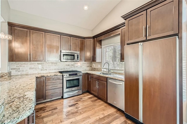8124 Bay Harbor Dr, Las Vegas, NV 89128 - kitchen featuring appliances with stainless steel finishes, a sink, vaulted ceiling, decorative backsplash, and light stone countertops