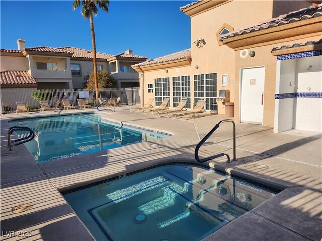 community pool featuring a hot tub, a patio, and fence