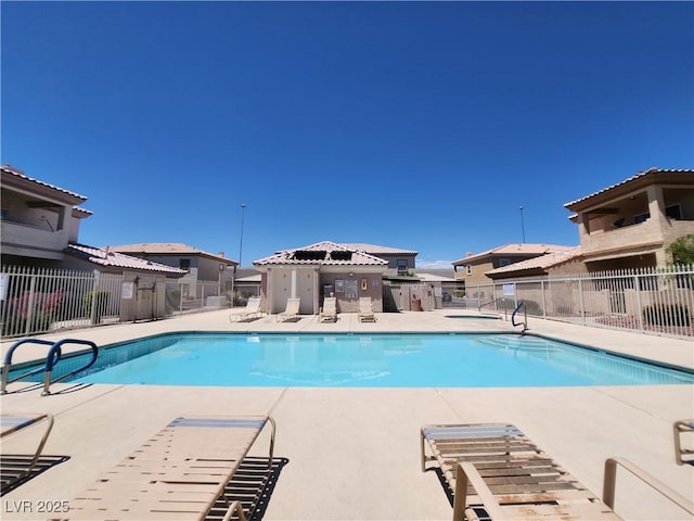 community pool with fence, a patio area, and a residential view