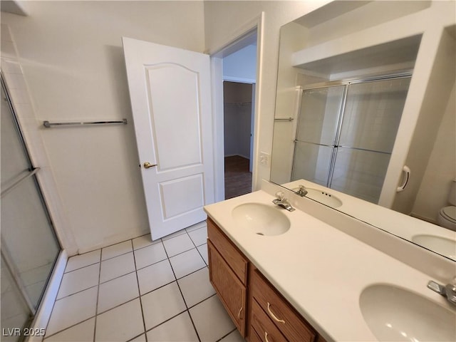 bathroom featuring a stall shower, double vanity, tile patterned floors, and a spacious closet
