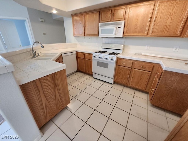 kitchen with white appliances, a sink, tile countertops, a peninsula, and light tile patterned floors