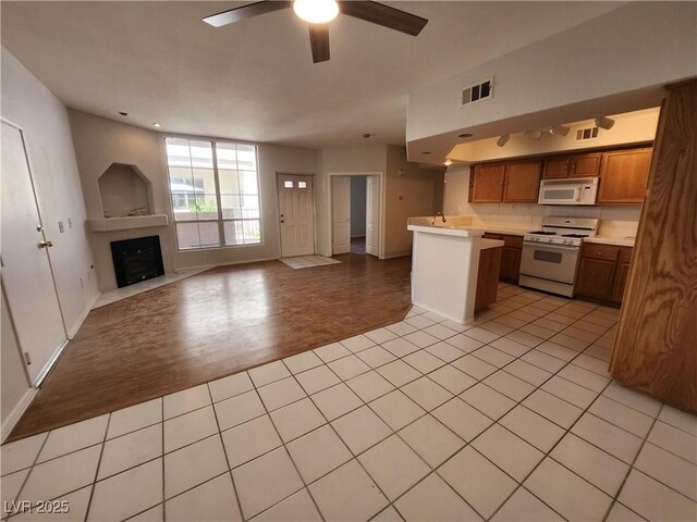 6908 Dorita Ave Unit 101, Las Vegas, NV 89108 - kitchen with white appliances, open floor plan, ceiling fan, light countertops, and a fireplace with flush hearth