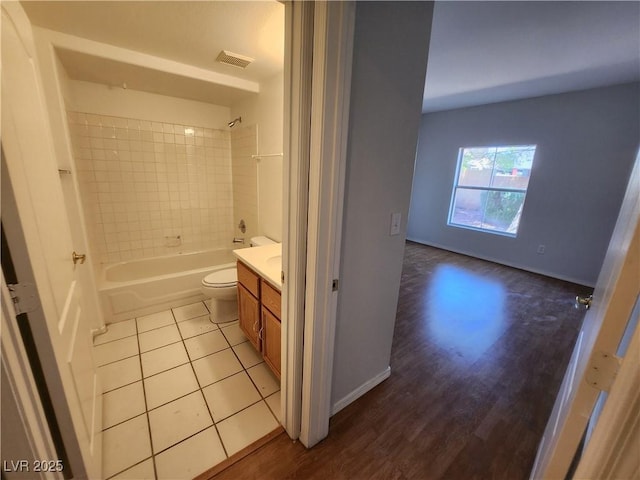 bathroom featuring wood finished floors, toilet, tub / shower combination, vanity, and baseboards