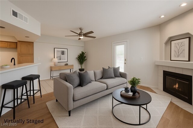 6908 Dorita Ave Unit 101, Las Vegas, NV 89108 - living area with ceiling fan, a tiled fireplace, light wood-style floors, recessed lighting, and baseboards