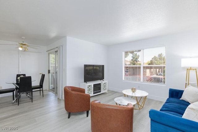 living area with healthy amount of natural light, light wood finished floors, an office area, and a ceiling fan