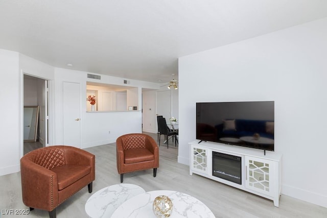 living area featuring wood finished floors, a ceiling fan, and baseboards