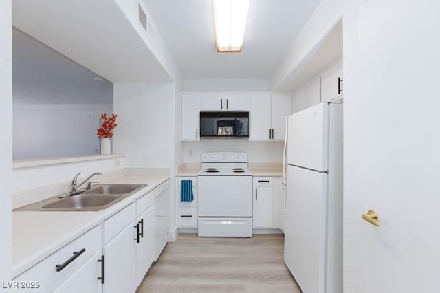 kitchen with white appliances, a sink, white cabinets, light countertops, and light wood-style floors