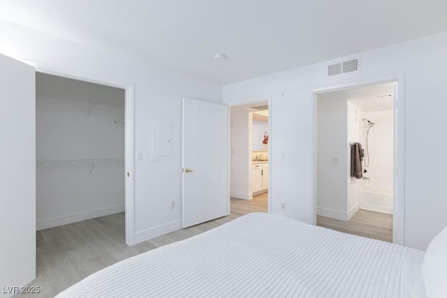 bedroom featuring light wood-type flooring, a spacious closet, a closet, and baseboards