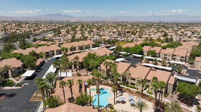 aerial view of property and surrounding area featuring a pool area, nearby suburban area, and a mountainous background