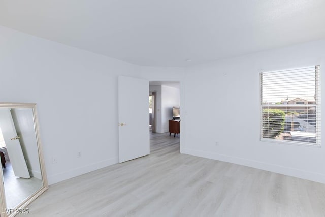spare room with light wood-type flooring, healthy amount of natural light, and baseboards