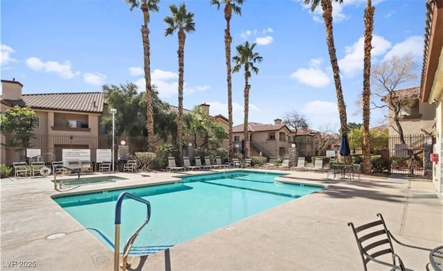 community pool with fence, a patio, and a residential view