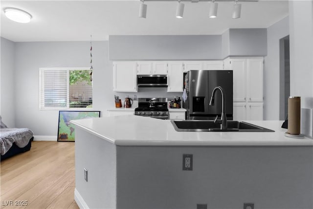 kitchen featuring stainless steel appliances, a sink, white cabinetry, and light countertops