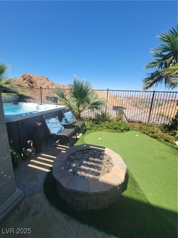 44 Moon Hill Dr, Henderson, NV 89011 - view of yard with fence, a putting green, a fire pit, and an outdoor hot tub