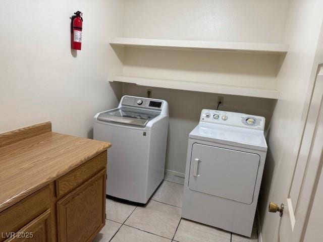 clothes washing area with washing machine and dryer and light tile patterned floors