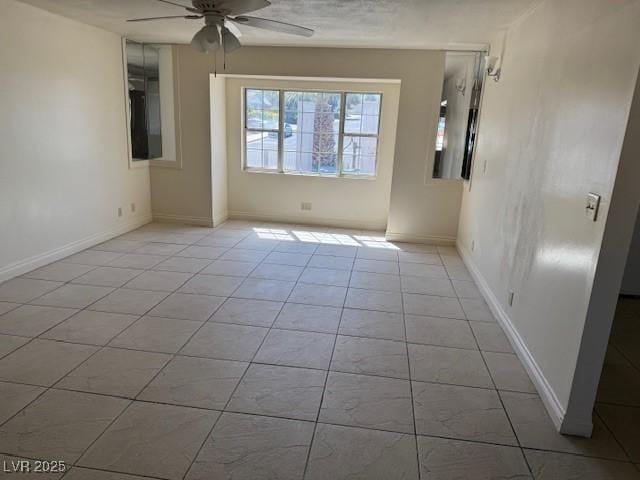 spare room featuring a ceiling fan, light tile patterned flooring, and baseboards
