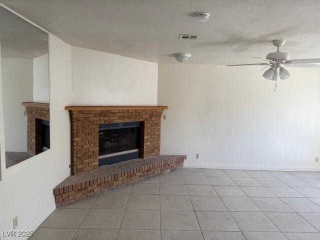unfurnished living room with a fireplace, tile patterned flooring, ceiling fan, and baseboards