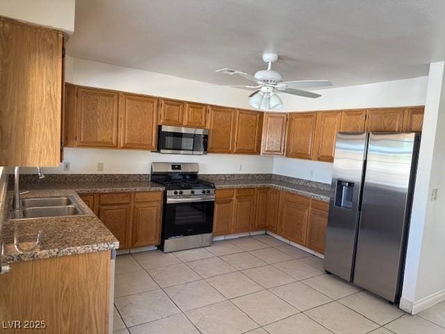 kitchen featuring appliances with stainless steel finishes, brown cabinetry, a sink, and light tile patterned floors