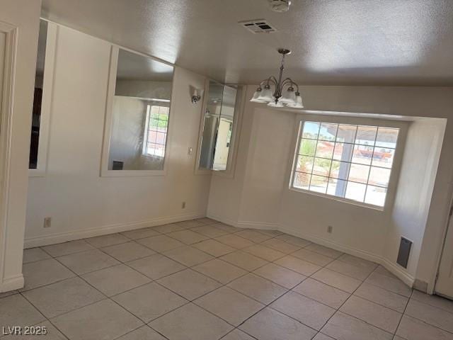 unfurnished room with a chandelier, light tile patterned flooring, and baseboards