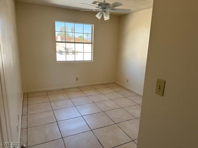 empty room featuring a ceiling fan, light tile patterned floors, and baseboards