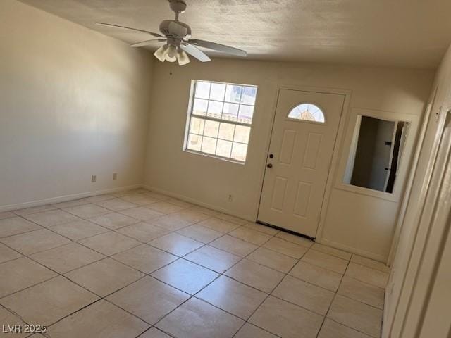 entrance foyer with a ceiling fan, light tile patterned floors, and baseboards