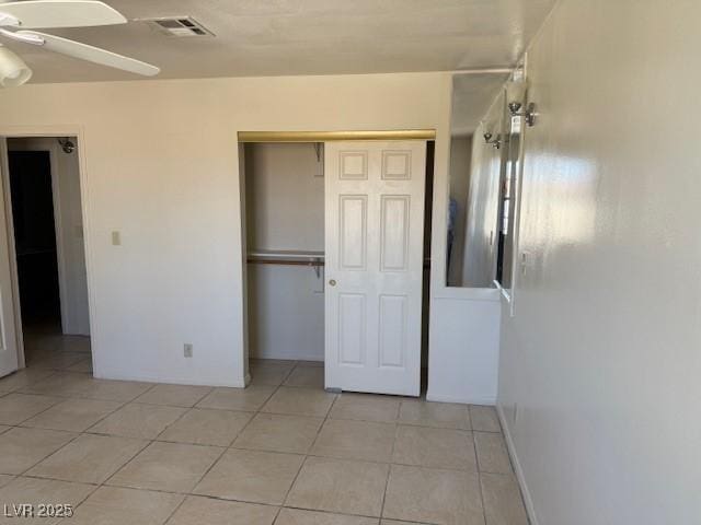 unfurnished bedroom with a closet, light tile patterned floors, and a ceiling fan