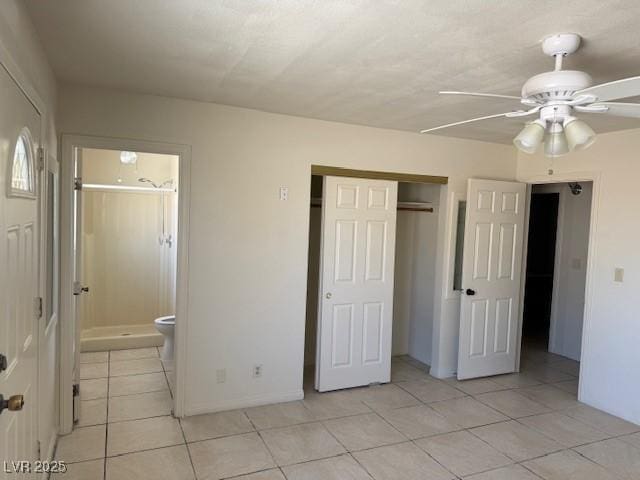 unfurnished bedroom featuring light tile patterned flooring, a closet, ensuite bath, a ceiling fan, and baseboards
