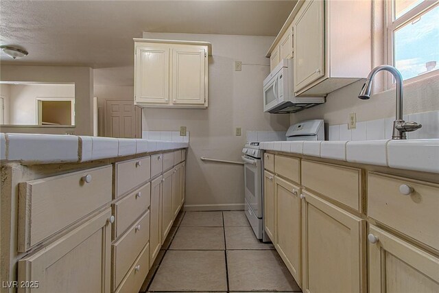 5170 S Pearl St, Las Vegas, NV 89120 - kitchen featuring range with gas stovetop, baseboards, light tile patterned floors, white microwave, and tile counters