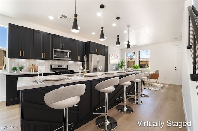 529 Fork Mesa Ct, Henderson, NV 89015 - kitchen with stainless steel appliances, dark cabinets, backsplash, light wood-type flooring, and recessed lighting