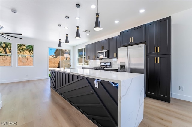 529 Fork Mesa Ct, Henderson, NV 89015 - kitchen with appliances with stainless steel finishes, baseboards, light wood finished floors, decorative backsplash, and light stone countertops