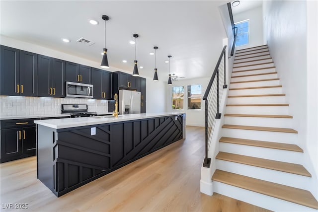 529 Fork Mesa Ct, Henderson, NV 89015 - kitchen featuring stainless steel appliances, a spacious island, decorative backsplash, light wood-type flooring, and pendant lighting